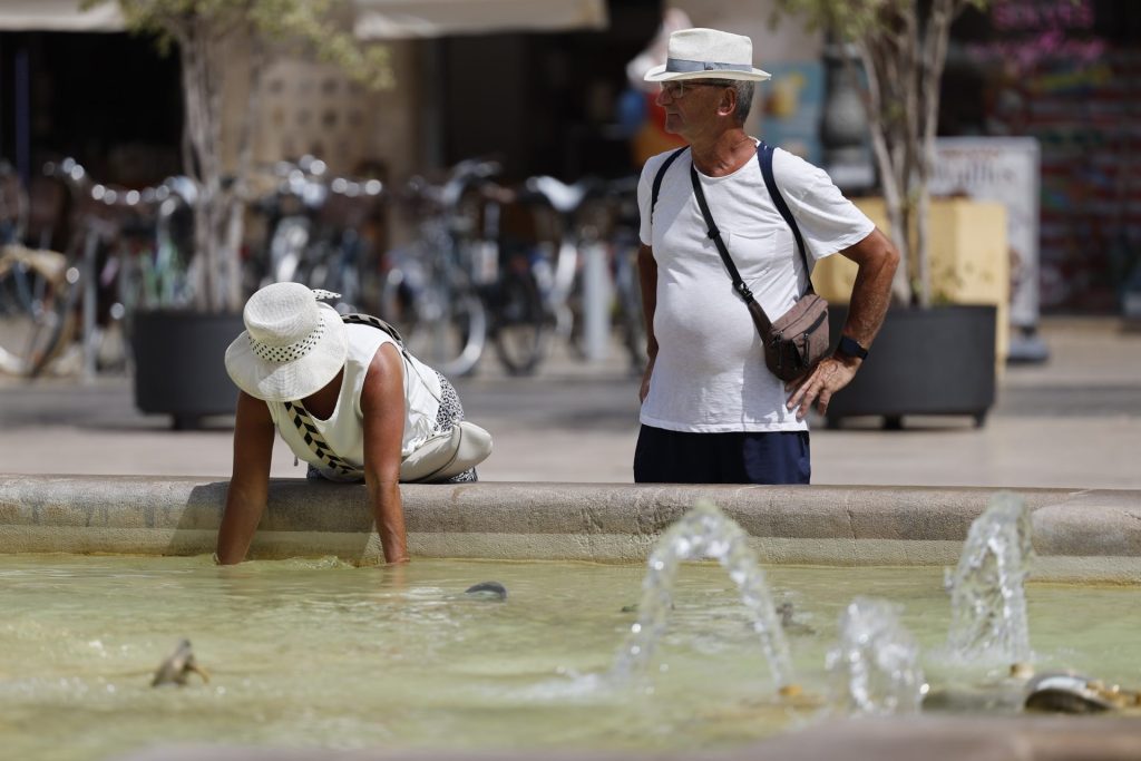 MADRID, 17/07/2026.- VArias personas se protegen del calor este viernes en Valencia. España irá sumando grados este fin de semana con un ascenso progresivo de las temperaturas que dejará más de 38 grados en zonas del este peninsular y Baleares y que podría desembocar, durante los primeros días de la próxima semana, en la tercera ola de calor del verano. EFE/ Ana Escobar