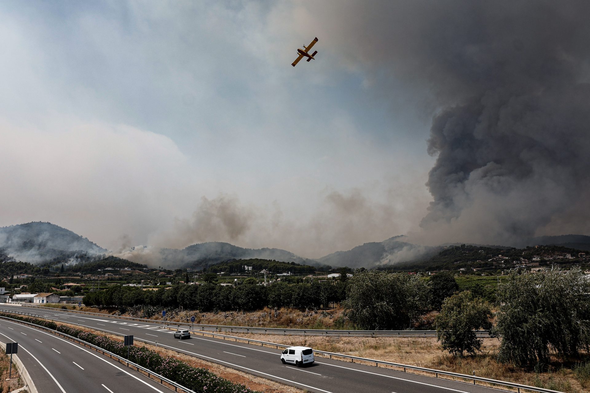 GRAFCVA5195. BETXÍ (CASTELLÓN), 26/07/2026.- Un hidroavión sobrevuela la autovía A-7 tras realizar una descarga de agua en Betxí en el frente del incendio declarado este sábado en la Vall d'Uixó (Castellón), y que ya lleva quemadas unas 4.300 hectáreas y cuyo perímetro supera los 40 kilómetros. EFE/Manuel Bruque