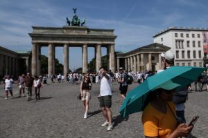 BERLIN (Germany), 27/06/2026.- A pedestrian shelters from the sun under an umbrella while walking past the Brandenburg Gate during high temperatures in Berlin, Germany, 27 June 2026. The German Weather Service (DWD) recorded a preliminary all-time record high of 41.3 degrees Celsius on 26 June near Saarbruecken. (Alemania) EFE/EPA/FILIP SINGER