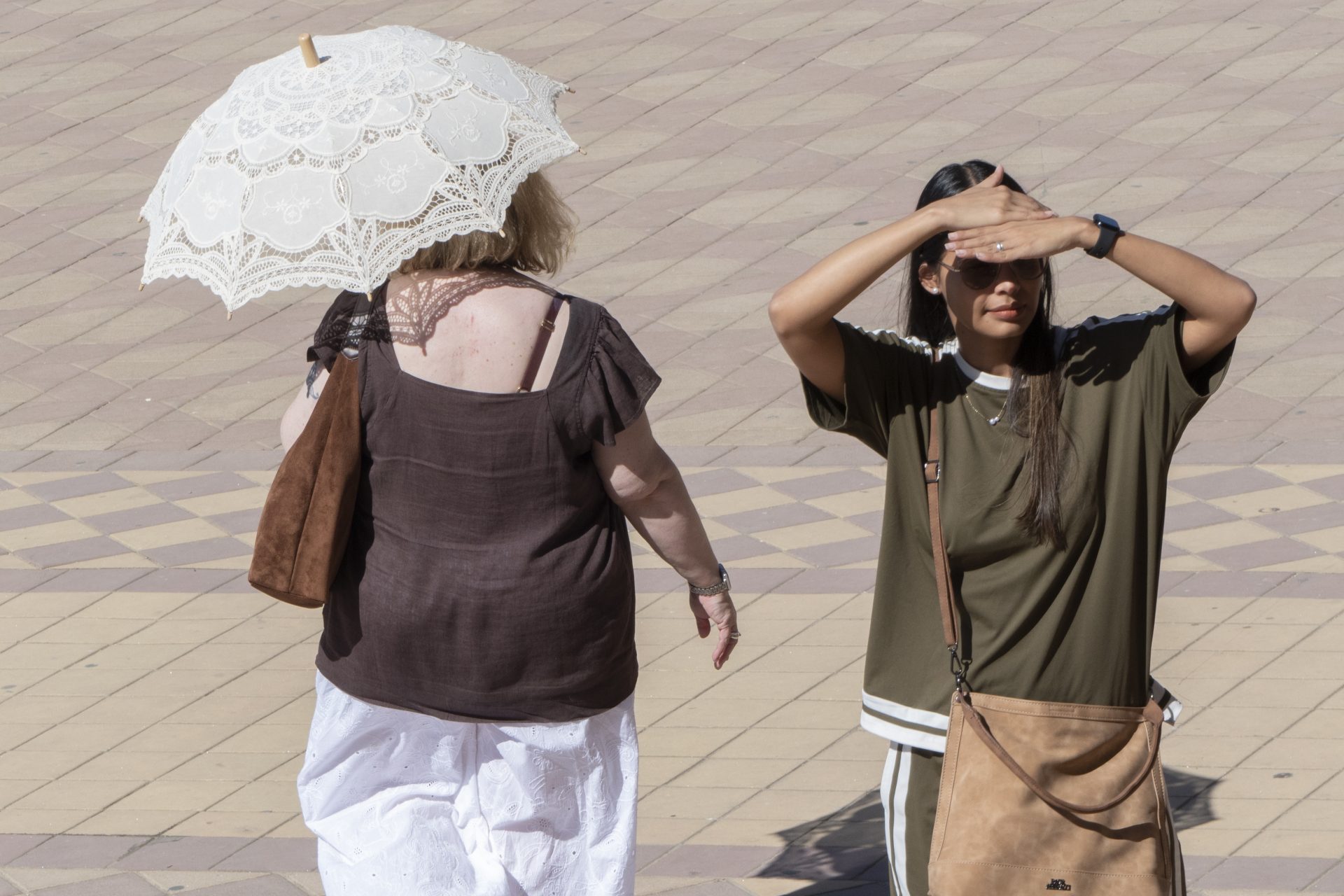 SEVILLA, 02/08/2026.- Varias personas se protegen del sol en Sevilla durante una nueva jornada de calor en la capital hispalense, pese a la bajada de algún grado, los avisos amarillos permanecen en la capital por altas temperaturas. EFE/ David Arjona