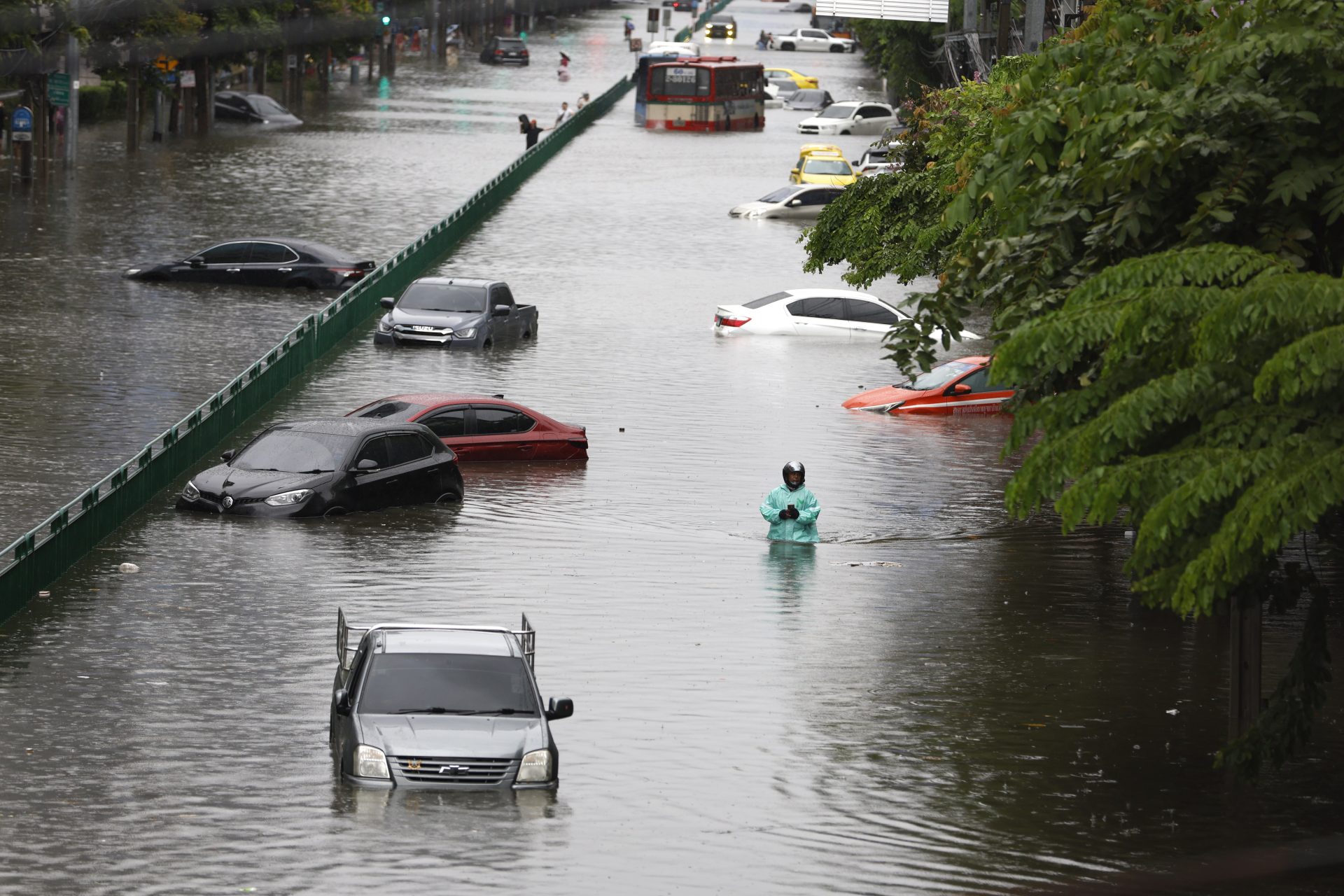 BANGKOK (Thailand), 26/09/2026.- A motorist wades through floodwater as submerged vehicles are abandoned during a downpour on a flooded major street, Phetchaburi Road in Bangkok, Thailand, 26 September 2026. All 50 districts in Bangkok have been declared flood disaster zones following the non-stop heavy downpour caused by a strong low-pressure system combined with seasonal monsoon patterns. (Inundaciones, Tailandia) EFE/EPA/RUNGROJ YONGRIT
